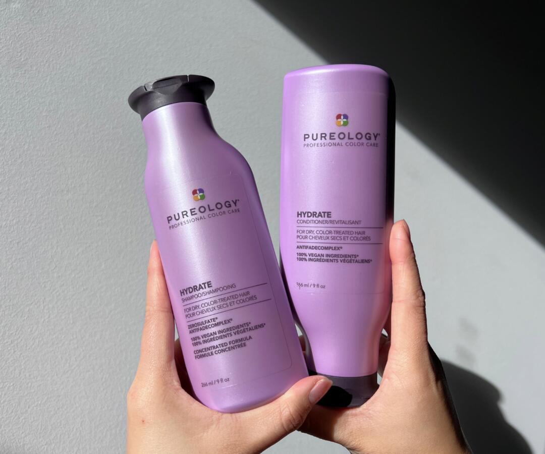 Person holding Pureology Hydrate Shampoo and Conditioner from Holy Grail Haircare