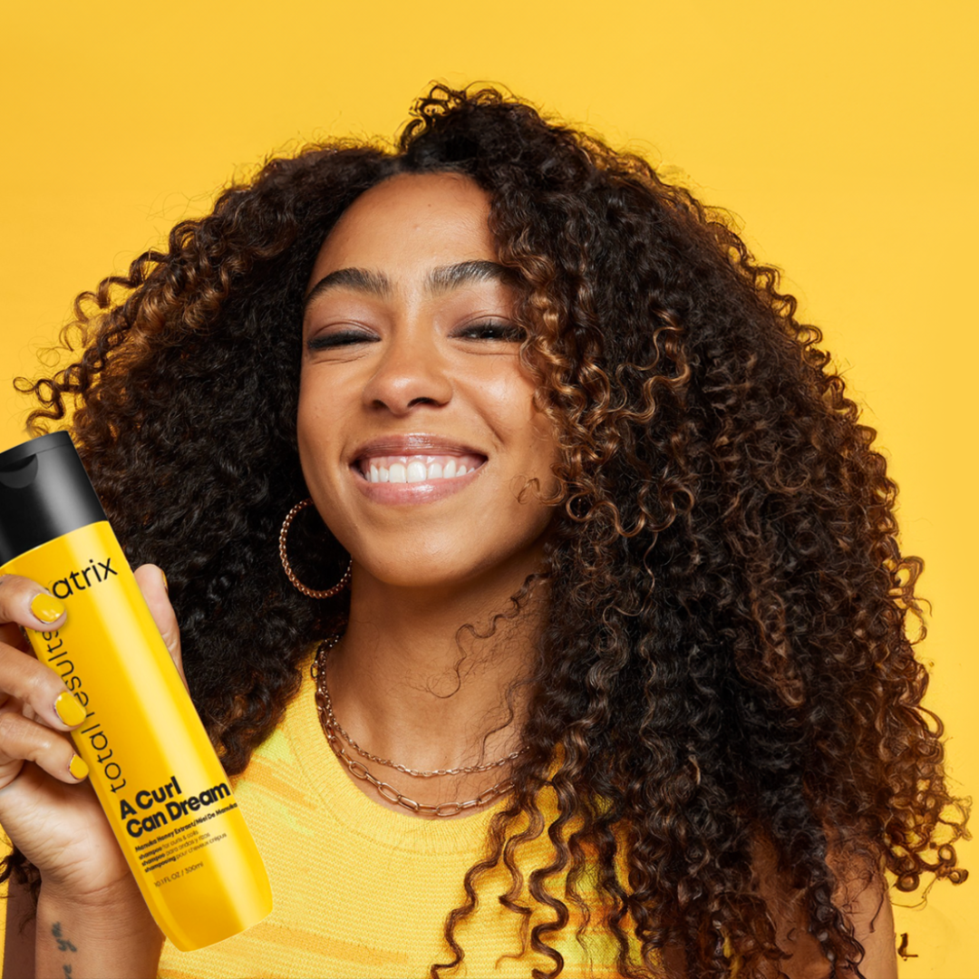 Smiling woman holding Matrix haircare product