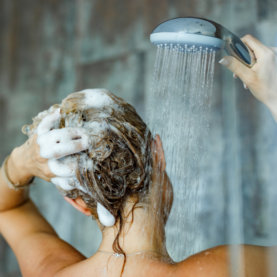 Young woman washing her hair in the shower