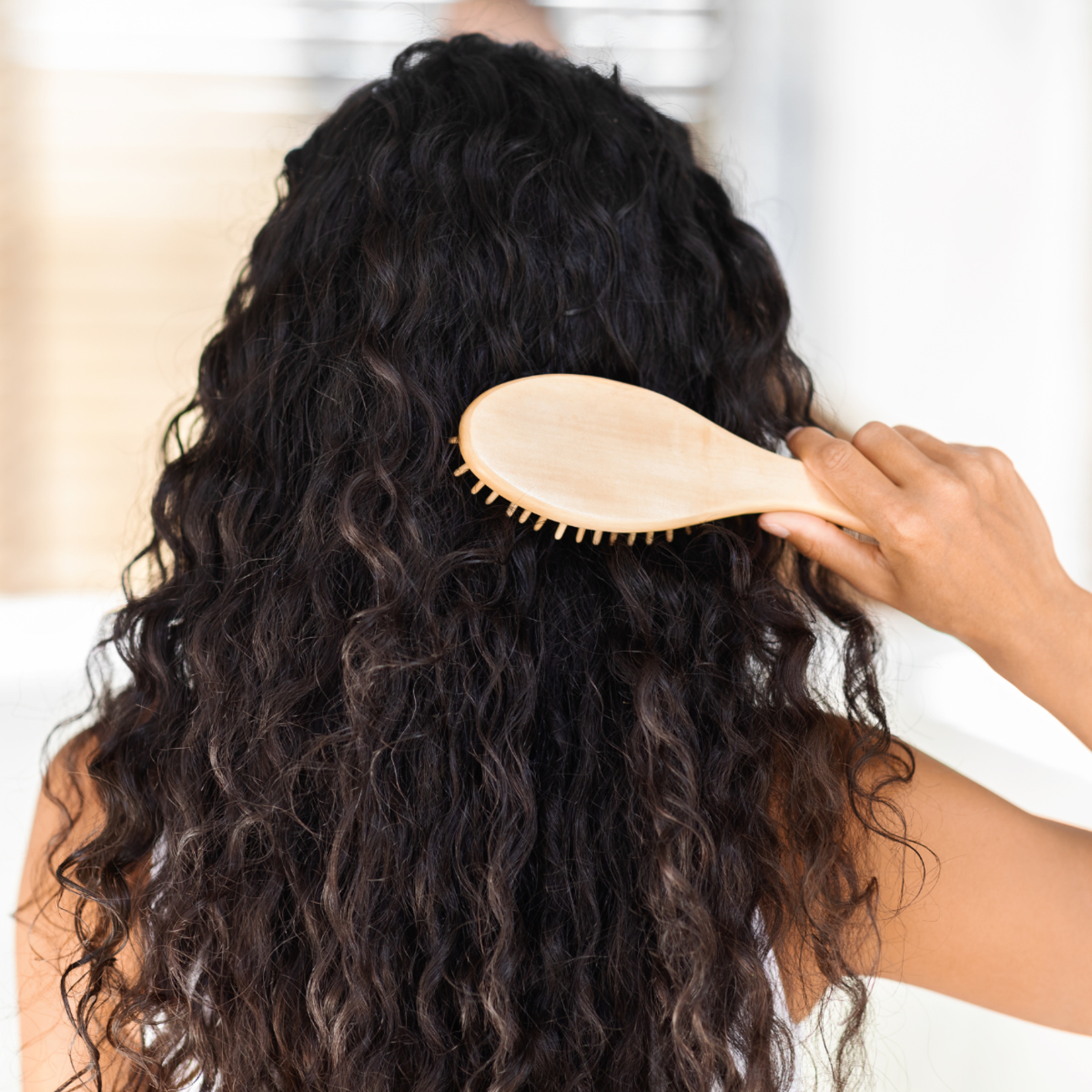 Young woman brushing very curly dark hair