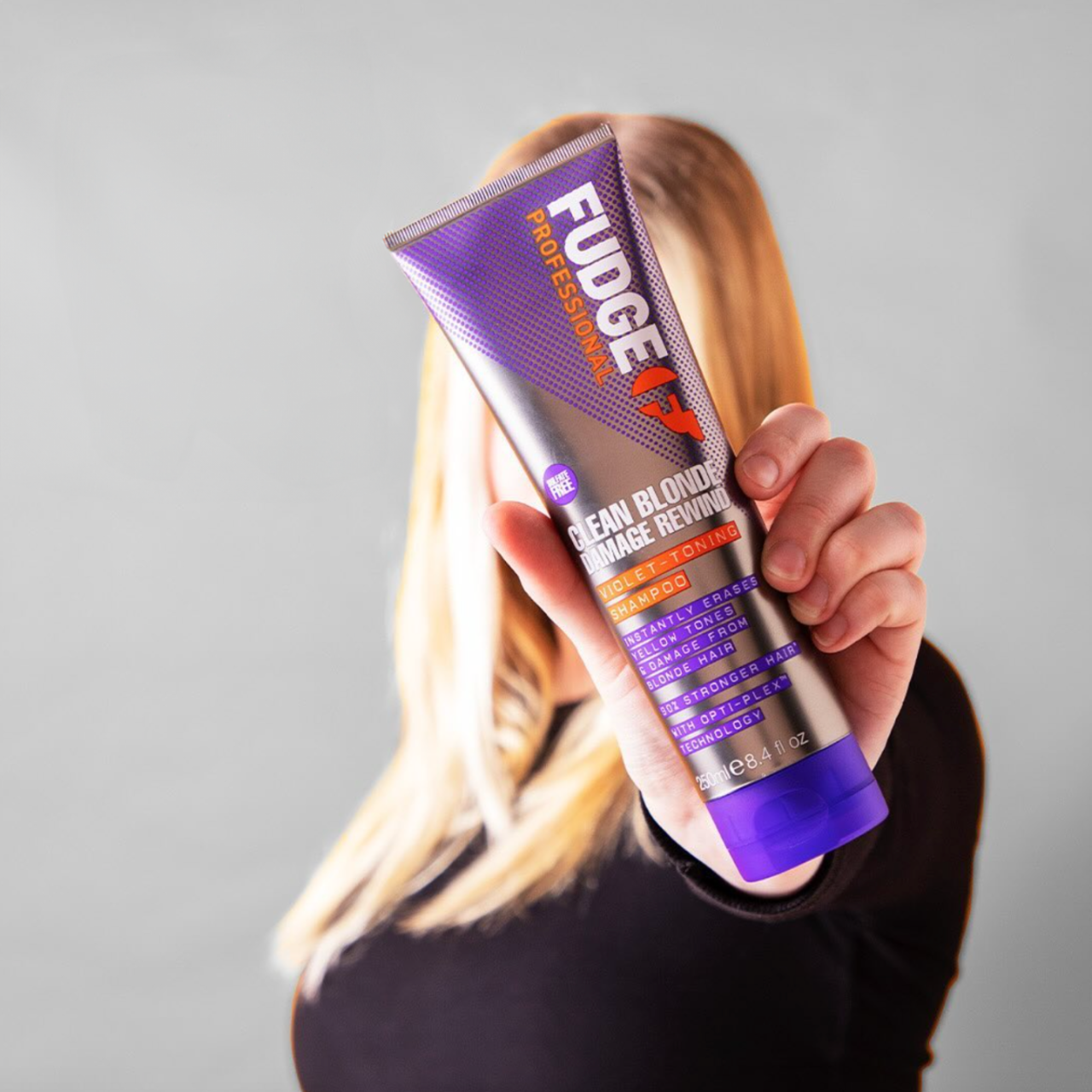 Woman holding Fudge Clean Blonde Damage Rewind Shampoo