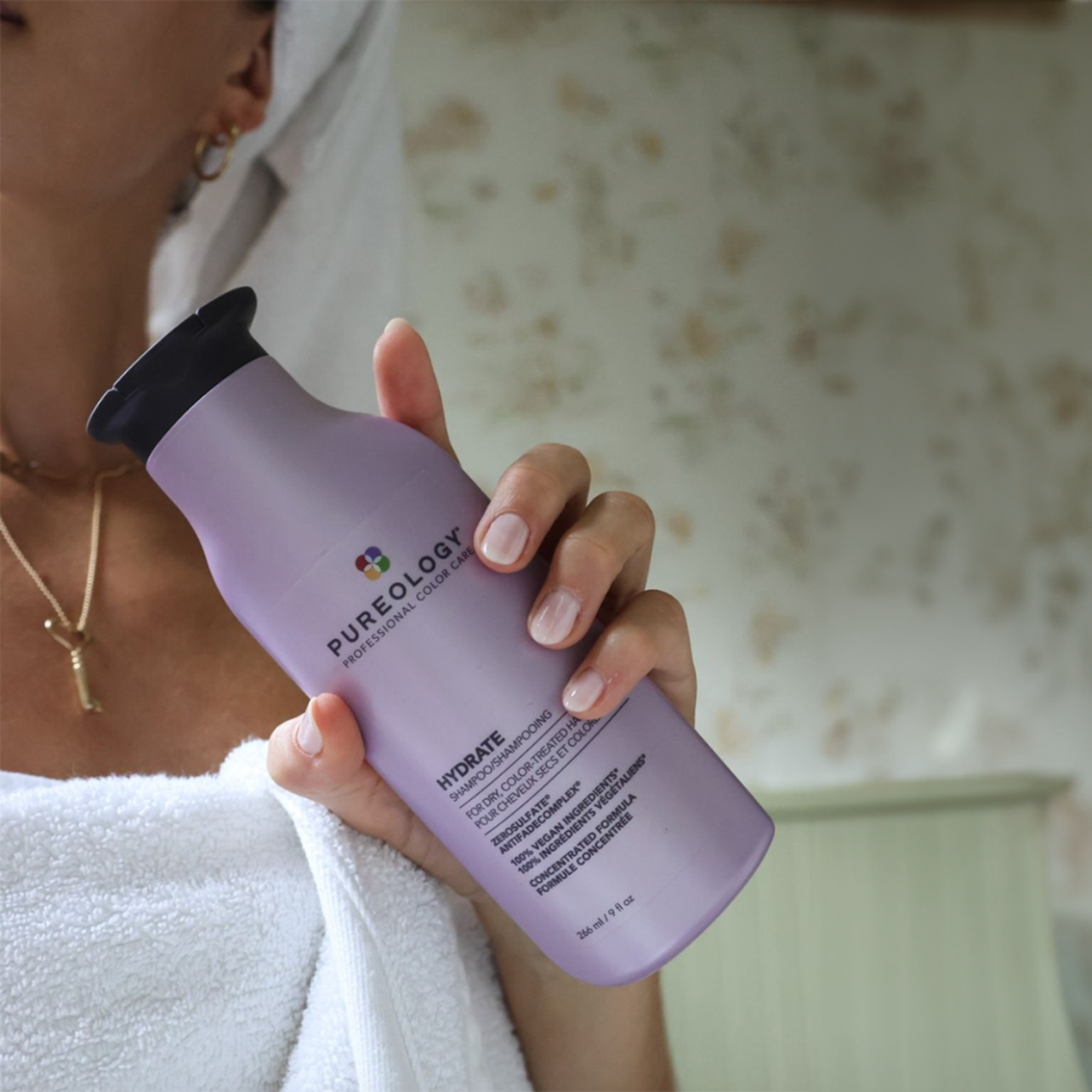 Woman holding Pureology Hydrate shampoo