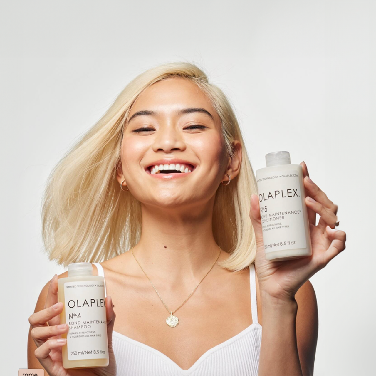 Smiling woman holding Olaplex No. 4 & No. 5