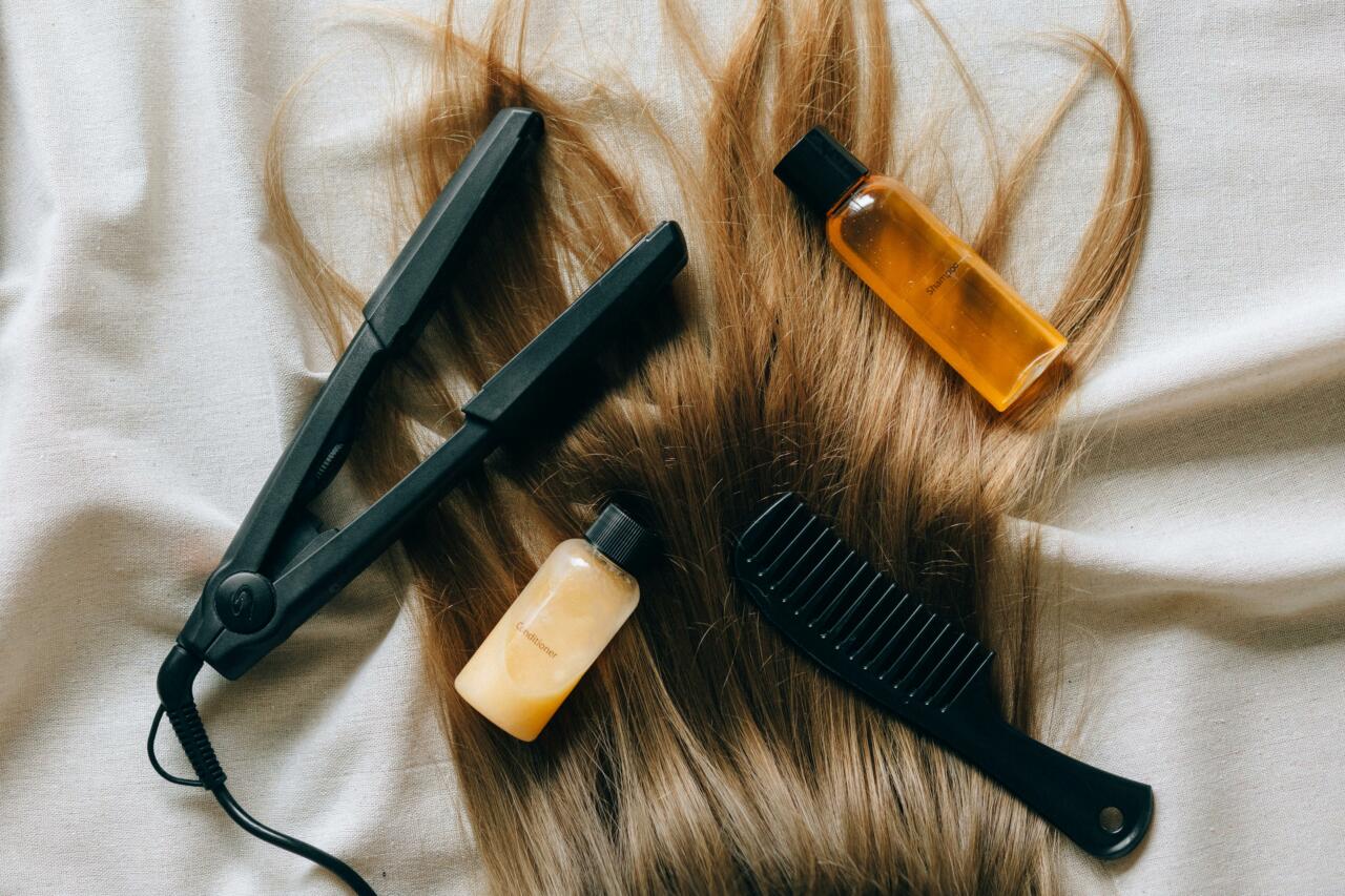 Person with blonde hair lying down amongst hair styling tools and products