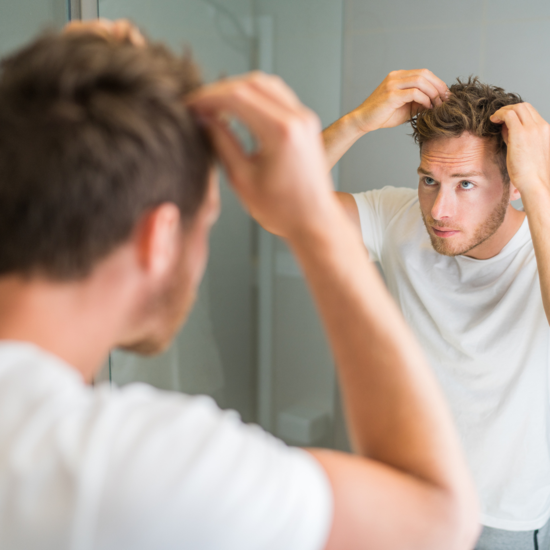 Young man checking his hair in the mirror