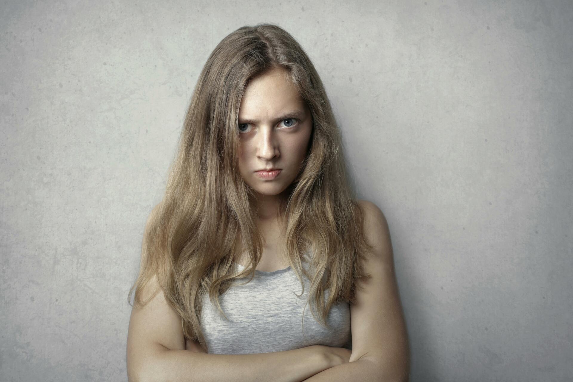 Young girl with dull blonde hair staring unhappily at the camera