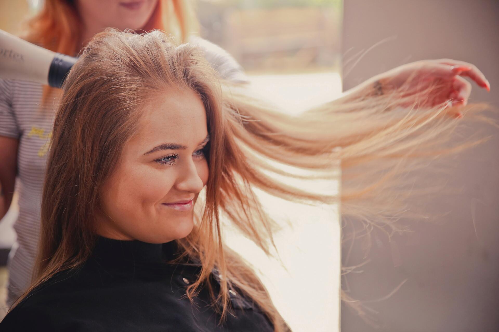 Young woman with blonde hair getting it blow dried at a salon