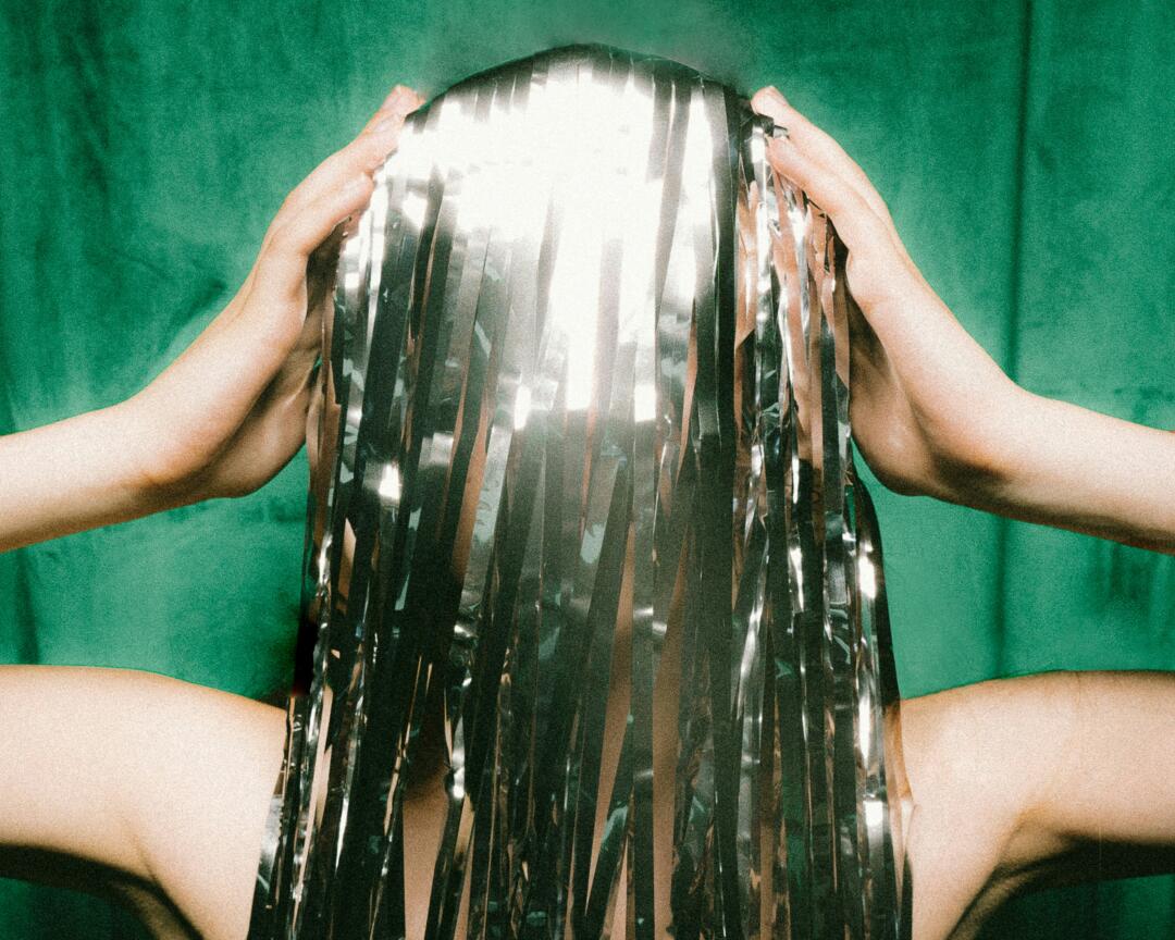 Person holding head with tinsel hair