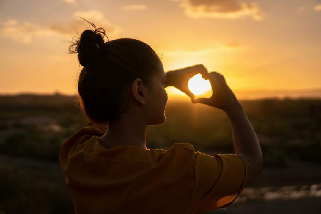 Young woman framing the sun with hands