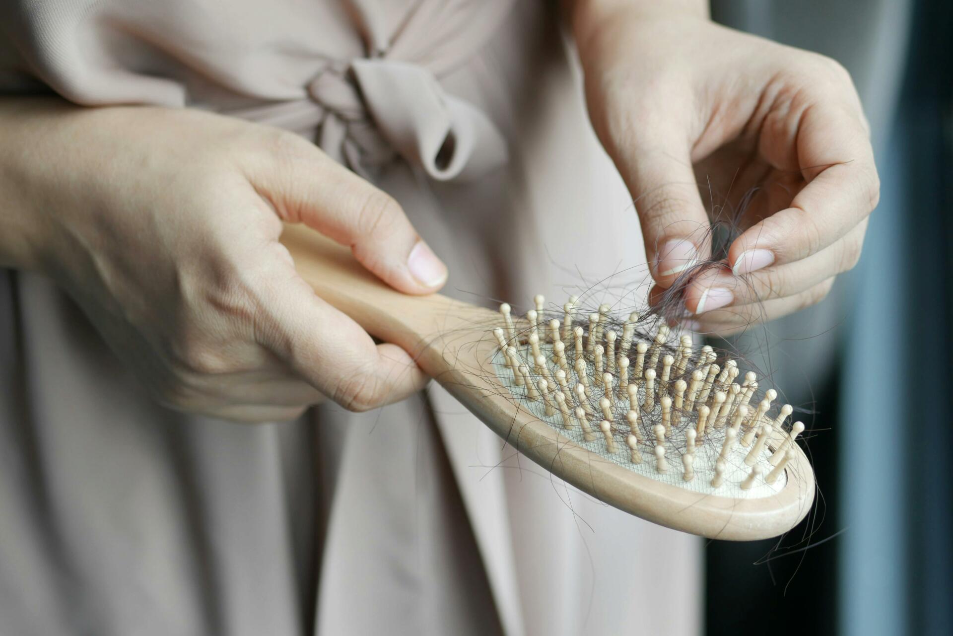 Woman holding brush with hair in the bristles